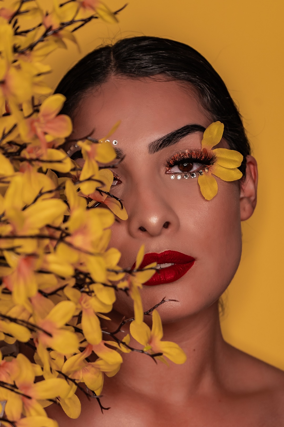 Mujer con maquillaje y flores amarillas posando