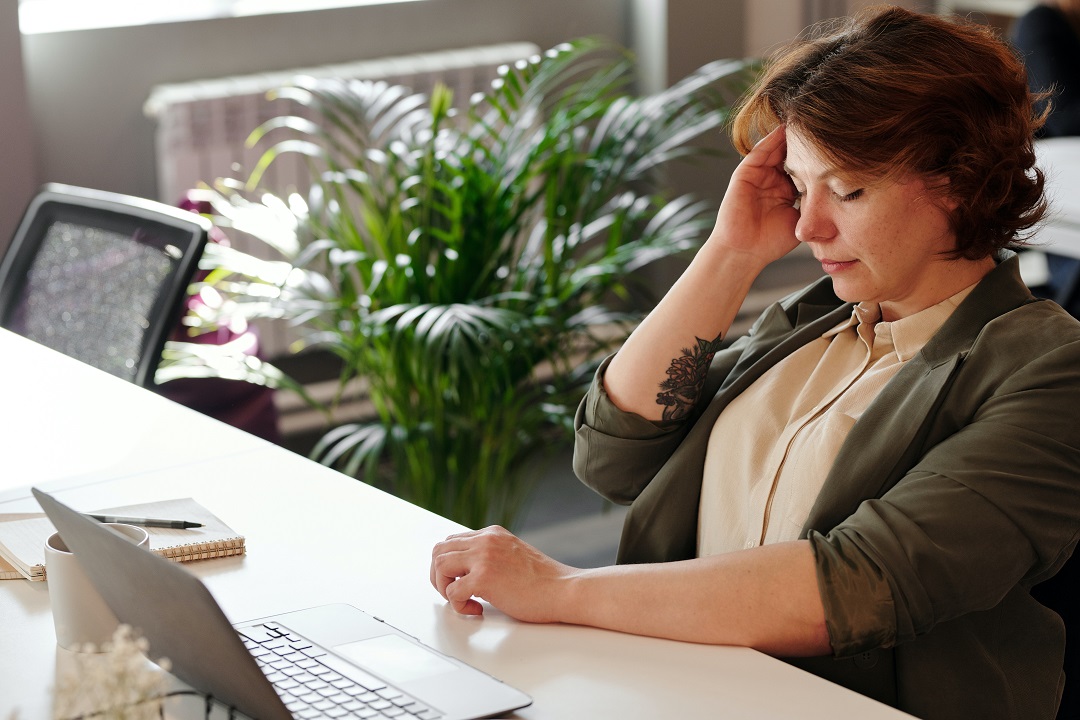 Mujer estresada en el trabajo frente a escritorio y laptop