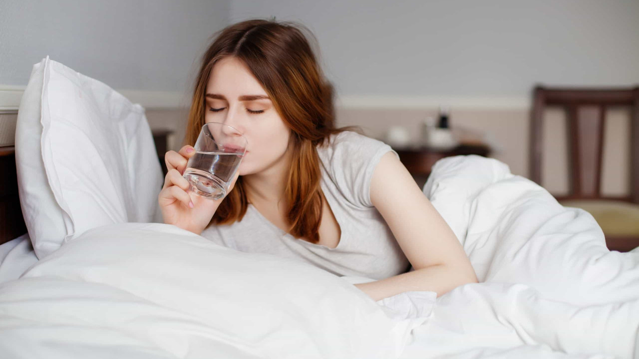 mujer tomando agua en la cama