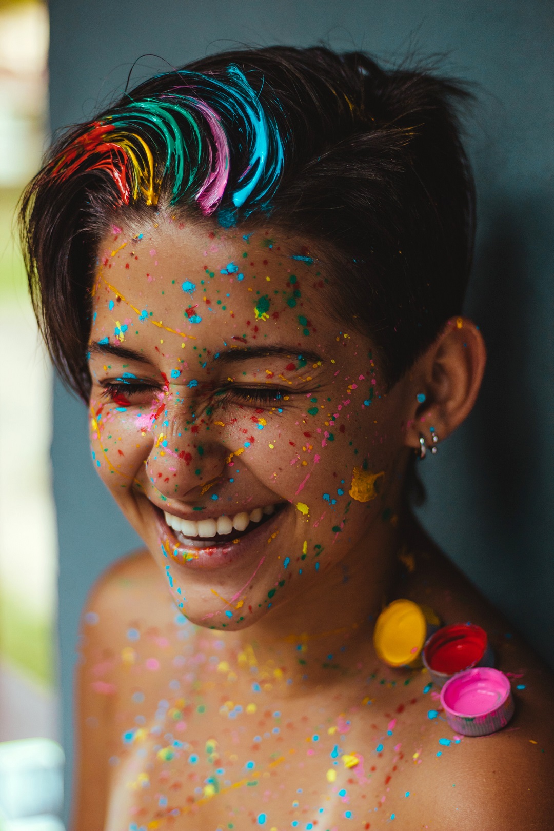 Mujer de cabello corto sonriendo riendo con pinturas de colores
