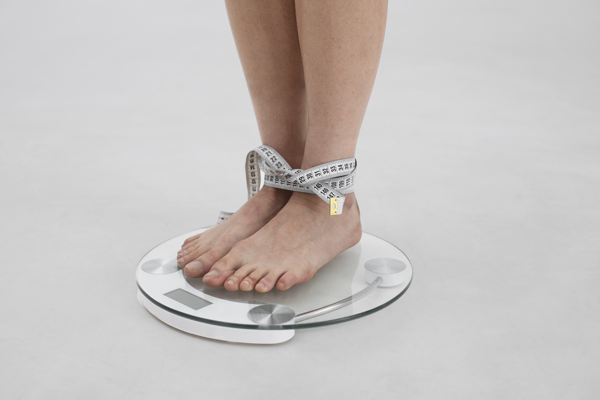 mujer con un trastorno alimentario con una báscula y cinta métrica