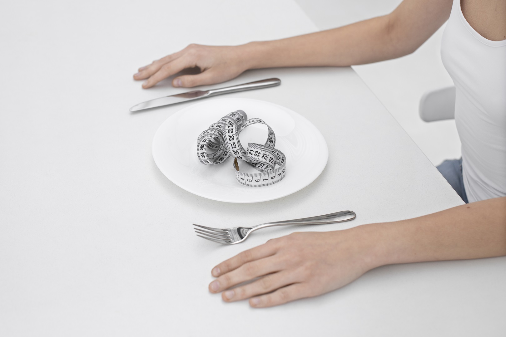 mujer joven con un trastorno alimentario con una cinta métrica en el plato