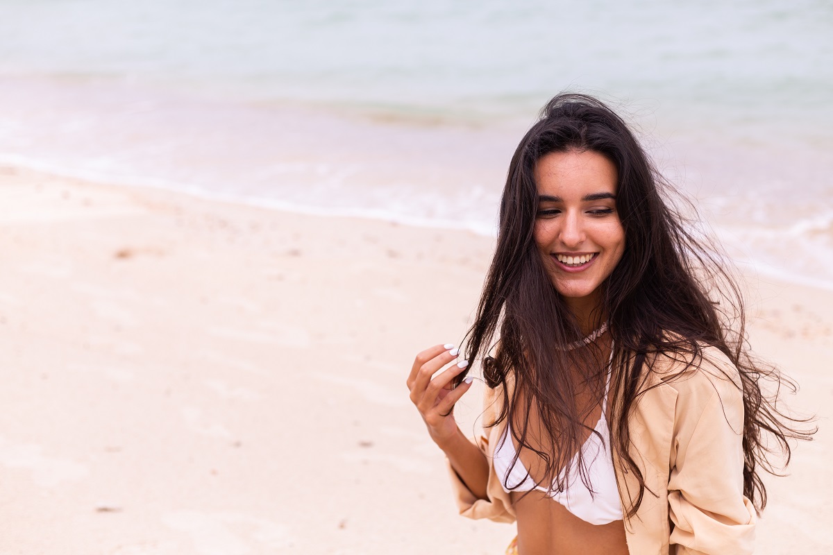 mujer en la playa sonriendo cabello pelo atardecer