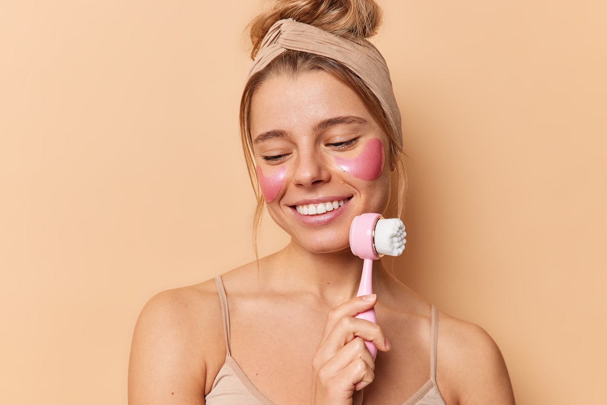 Mujer masajeador facial rostro cara skincare fondo rosa