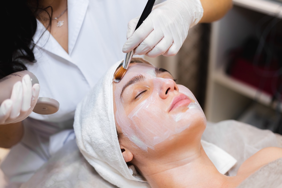 Facial esteticista aplica una mascarilla en el rostro de una clienta en un salón de belleza spa