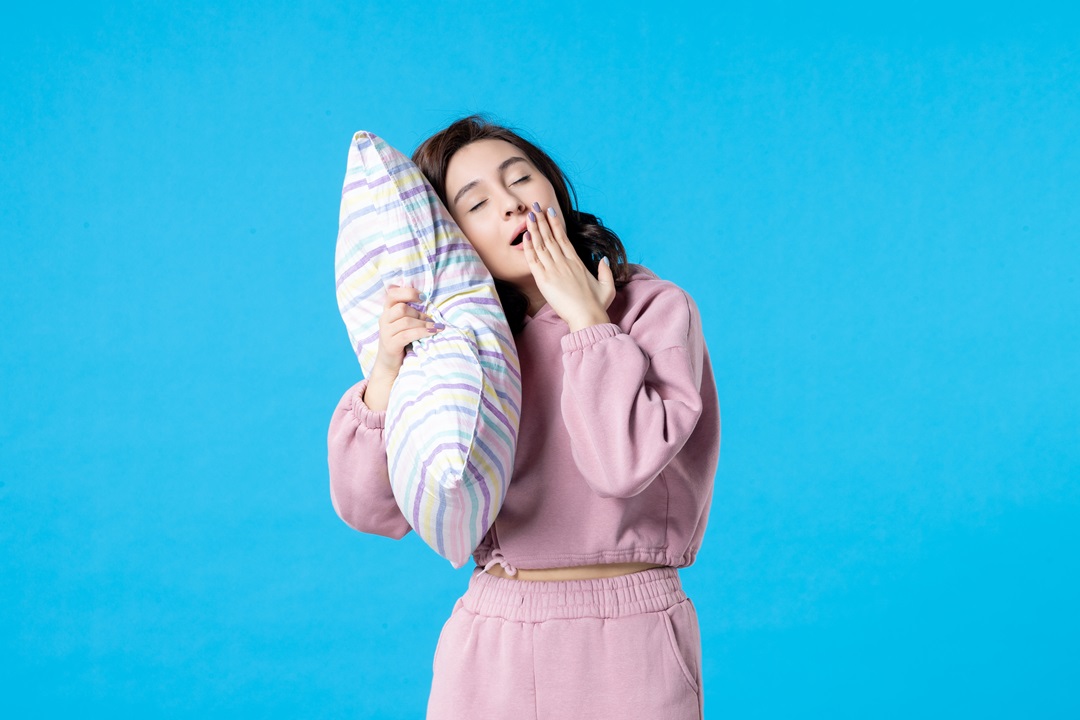 mujer en pijama sosteniendo almohada dormir descanso cansancio agotamiento